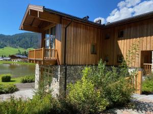 a wooden house with a balcony and a lake at ClubHotel Hinterthal Am FlorySee 12 in Hinterthal