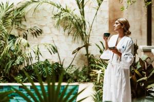une femme en robe blanche tenant un verre de vin dans l'établissement CIGNO HOTEL BOUTIQUE- Adults Only, à Mérida