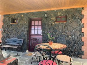 un patio con mesa, sillas y pared de piedra. en Casita La Enramada, en Sabinosa