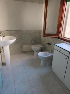 un bagno con due wc, un lavandino e uno specchio di Casa Bellini Oristano a Oristano