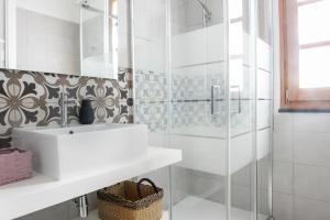 ein weißes Bad mit einem Waschbecken und einer Dusche in der Unterkunft Casa Mediterranea in Nurachi