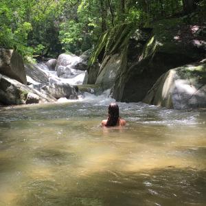 Una donna che nuota in un fiume vicino a una cascata di Reserva Natural La Esperanza a Girocasaca