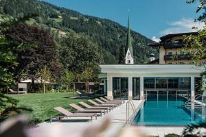 un resort con piscina e sedie a sdraio di Hotel Bräu a Zell am Ziller