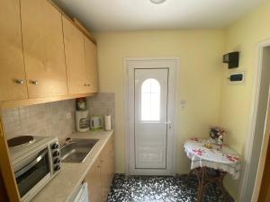 uma cozinha com um lavatório e uma porta com uma mesa em The Condo Palace in Agia Marina em Agia Marina