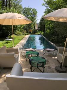 einen Pool mit Stühlen, Tischen und einem Sonnenschirm in der Unterkunft La Manufacture Royale 1739 in Montolieu