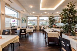 un restaurante con mesas y sillas blancas y ventanas en Hotel Thorenberg, en Lucerna