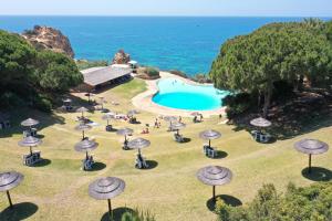 un grupo de mesas y sombrillas junto a una piscina en Casa da Prainha - private pool, next to the beach, en Alvor