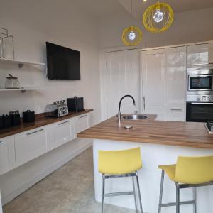 a kitchen with white cabinets and yellow bar stools at No 9 retreat in Prestwick