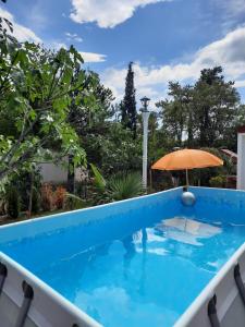 a blue swimming pool with an umbrella and an umbrella at Ferienhaus Nikola in Jadranovo