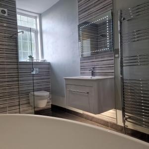 bagno con vasca, lavandino e specchio di No 9 retreat a Prestwick