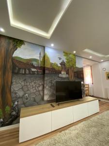 a living room with a tv and a mural at Apartments Natural and Bungalows in Sarajevo