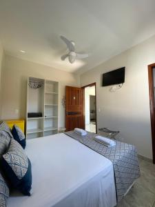 1 dormitorio con 1 cama blanca grande y TV de pantalla plana en Pousada Serrate, en Ubatuba