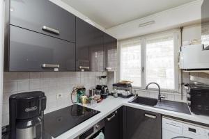 a kitchen with black cabinets and a sink at Spacious T3 with view in the heart of the city! in Charenton-le-Pont