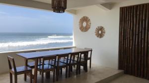a dining room with a table and chairs and the ocean at LAOLA SURF CAMP EL SUNZAL in La Libertad