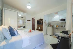 a bedroom with a white bed and a kitchen at Pousada Recanto da Família in Natal