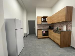 cocina con armarios de madera y nevera blanca en Wels Inn City Apartments, en Wels