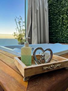 a wooden tray with a bottle of soap and a heart shaped bowl at Pousada e Restaurante Vista Turquesa in Arraial do Cabo