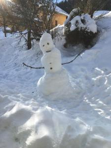Ein Schneemann steht im Schnee in der Unterkunft Gîte La Grange in Méaudre