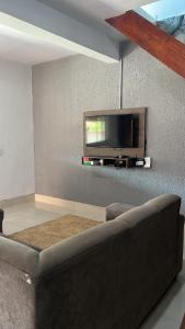 een woonkamer met een bank en een tv aan de muur bij KasaNivea in Pirenópolis