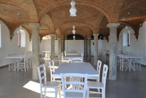 Agriturismo Mascudiera في فيورينزولا دردا: غرفة بطاولات بيضاء وكراسي في مبنى