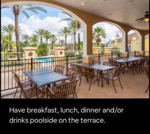 un patio con mesas, sillas y palmeras en Serene family friendly townhouse in the wonderful Regal Palms, en Davenport