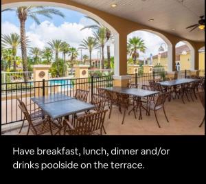 a patio with tables and chairs and palm trees at Serene family friendly townhouse in the wonderful Regal Palms in Davenport