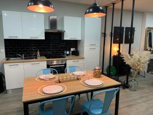 a kitchen with a wooden table and blue chairs at Les Apparts de Bastide 35B in Villeneuve-sur-Lot