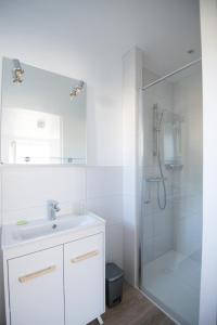 a white bathroom with a sink and a shower at Les Chambres de Lourmel in Pontivy