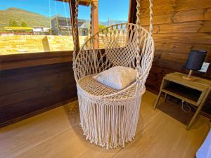 a white wicker chair sitting in a room with a window at Chalé Miragem dos Canyons in Praia Grande