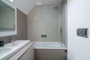 a bathroom with a shower and a tub and sink at GuestReady - Chic flat in the heart of Kensington in London