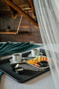 a tray with two cups and fruit on a bed at Casa Hayhu in Mahahual