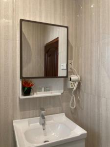 Airport West Hotel في آكرا: حمام مع حوض ومرآة على الحائط