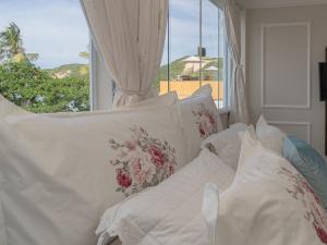 a white bed with pillows in front of a window at Pousada Recanto da Família in Natal