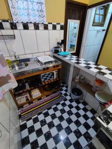 uma cozinha com piso em xadrez preto e branco em Morada das Flores Chalé/Kitnet na Ilha do Mel