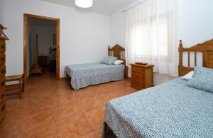 a bedroom with two beds and a dresser and a window at Casa Sagrario in Santa María de los Llanos