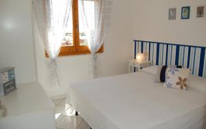 1 dormitorio con cama blanca y ventana en Casa Bellavista, en Monte Nai