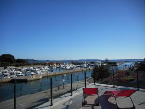 two red chairs sitting on a balcony overlooking a marina at SUPERBE VILLA VUE MER JUSQU'A 14 COUCHAGES La LONDE LES MAURES Entre HYERES et Le LAVANDOU 4 Etoiles PISCINE CHAUFFEE in La Londe-les-Maures +39 photos