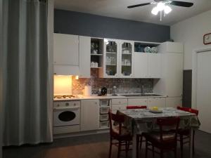 a kitchen with white cabinets and a table with chairs at Casa vacanze "Ulivi nel Mare" in Sciacca