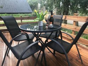a table and chairs on a deck with a bottle of wine at Foxes Sea Side Retreat Deluxe Chalet is a lovely holiday home tucked away on the Kent Coast in Kingsdown