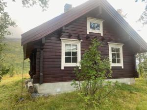 uma pequena casa de madeira com duas janelas num campo em Log Cabin Close to Nature em Finnsnes