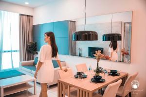 a woman standing in a living room with a dining room at The Robertson Kuala Lumpur by White Forest Suites in Kuala Lumpur