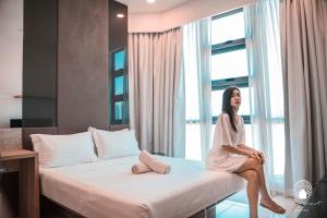 a woman sitting on a bed in a hotel room at The Robertson Kuala Lumpur by White Forest Suites in Kuala Lumpur