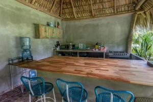 a kitchen with a large wooden counter with chairs at La Canasta in El Zonte