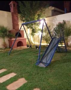 a slide in the grass in a yard at night at Danat Alnakheel Chalet in Buraydah