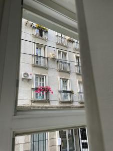 ein Fenster mit Blick auf ein Gebäude mit Blumen auf den Balkonen in der Unterkunft City Apartments Ana in Belgrad