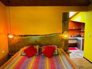 een slaapkamer met een bed met 2 rode kussens bij El Sol Monteverde in Monteverde Costa Rica