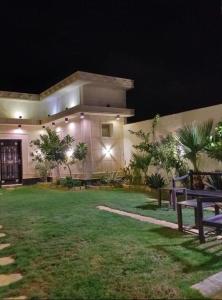a house with a lawn in front of it at night at Danat Alnakheel Chalet in Buraydah