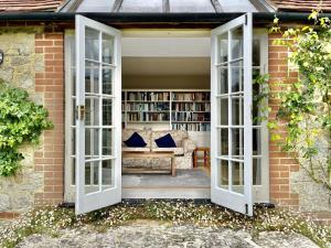 an open door leading into a library with a couch at Library Cottage in Thakeham