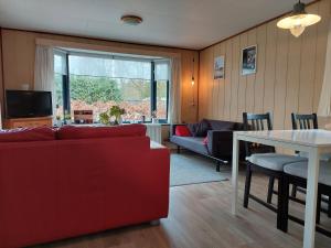 een woonkamer met een rode bank en een tafel bij Chalet Bosrust in Wolfheze