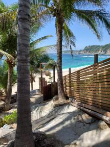a sandy beach with palm trees and the ocean at Hotel Bendita Luna Salchi in Cuatunalco